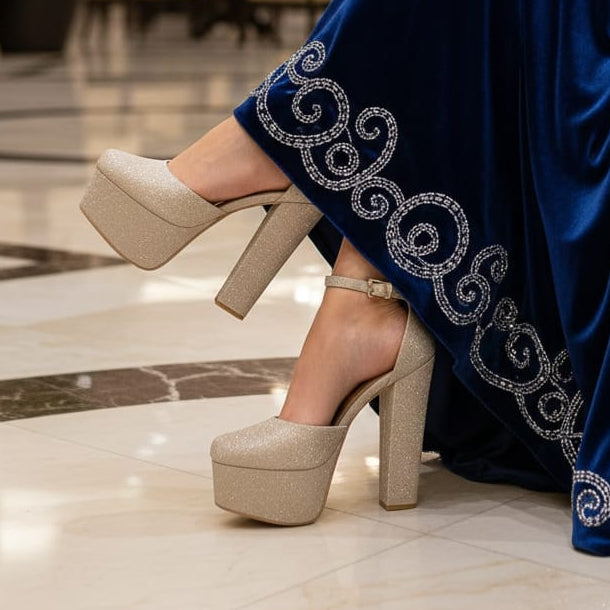 Person wearing a blue dress with intricate patterns and beige high-heeled shoes in an indoor setting.