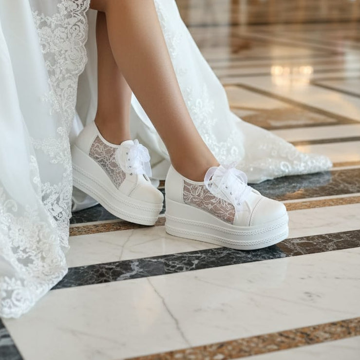 White lace sneakers worn with a white dress on a marble floor.