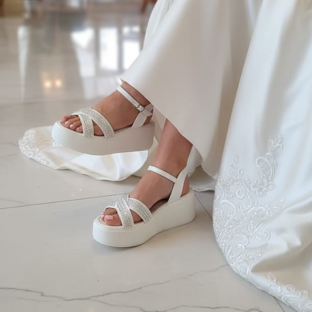Bridal White sandals worn by a Bride  in a white dress on a marble floor.