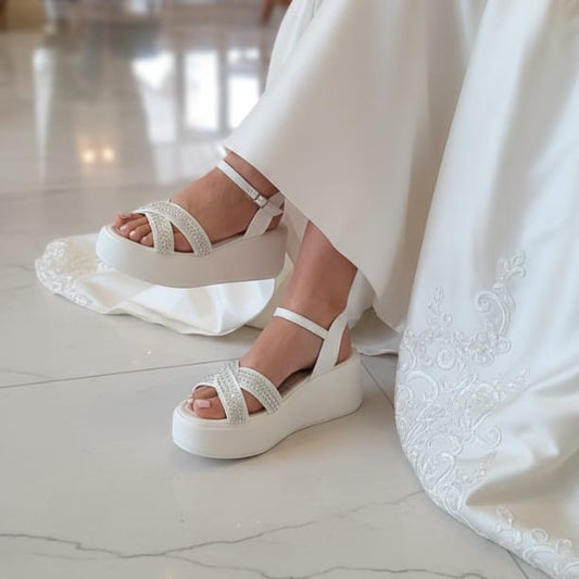 Bridal White sandals worn by a Bride  in a white dress on a marble floor.
