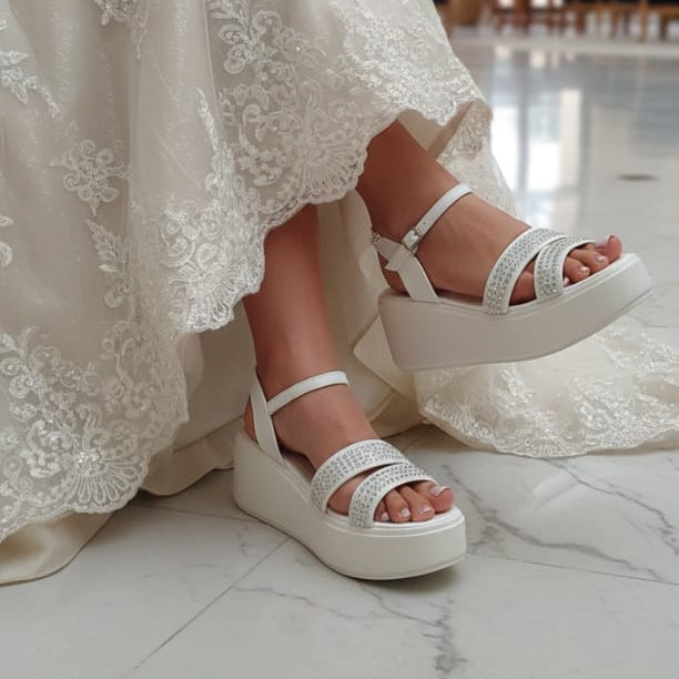Bride wearing a white lace dress and Bridal white platform sandals in an indoor setting.