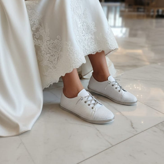 Person wearing a white lace dress and white sneakers in an indoor setting.