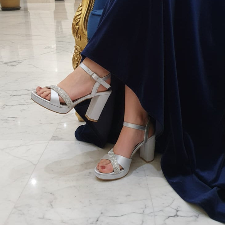 Person wearing silver high-heeled sandals in a luxurious interior setting