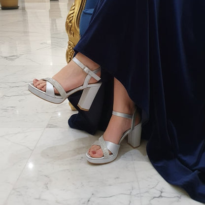 Person wearing silver high-heeled sandals in a luxurious interior setting