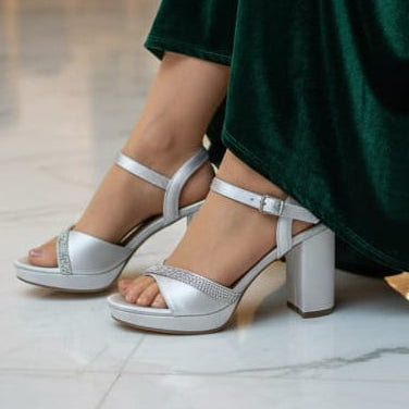 green dress and silver sandals in an elegant indoor setting.