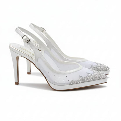 White high-heeled shoes with studded details on a white background