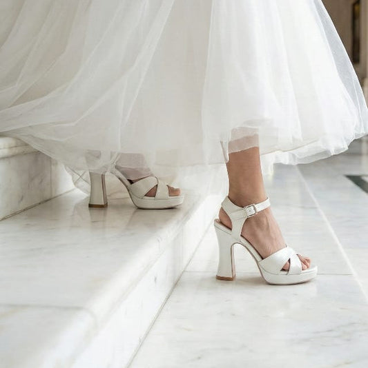 White wedding dress with high-heeled shoes on a marble floor