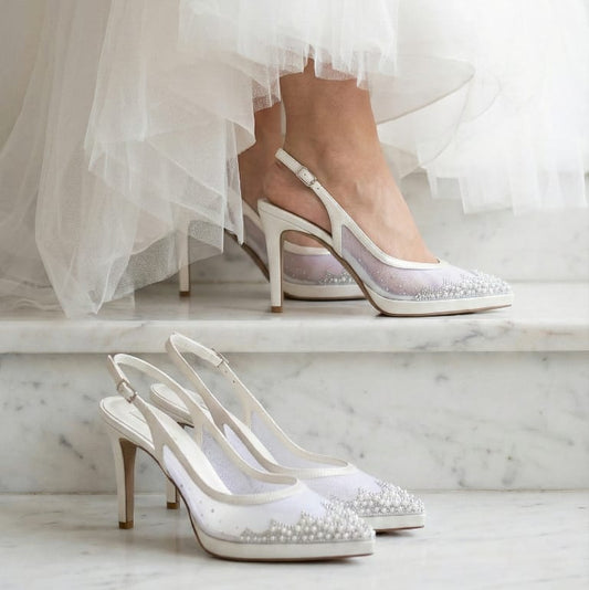 White wedding shoes with pearl details on a marble staircase
