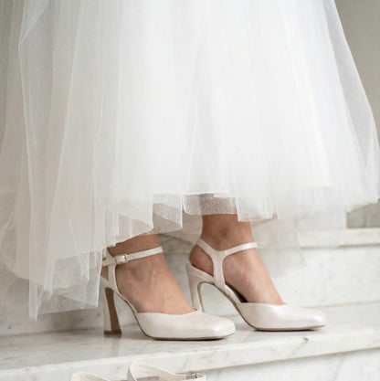 Pair of Pearl white high-heeled shoes on a marble surface with a light background