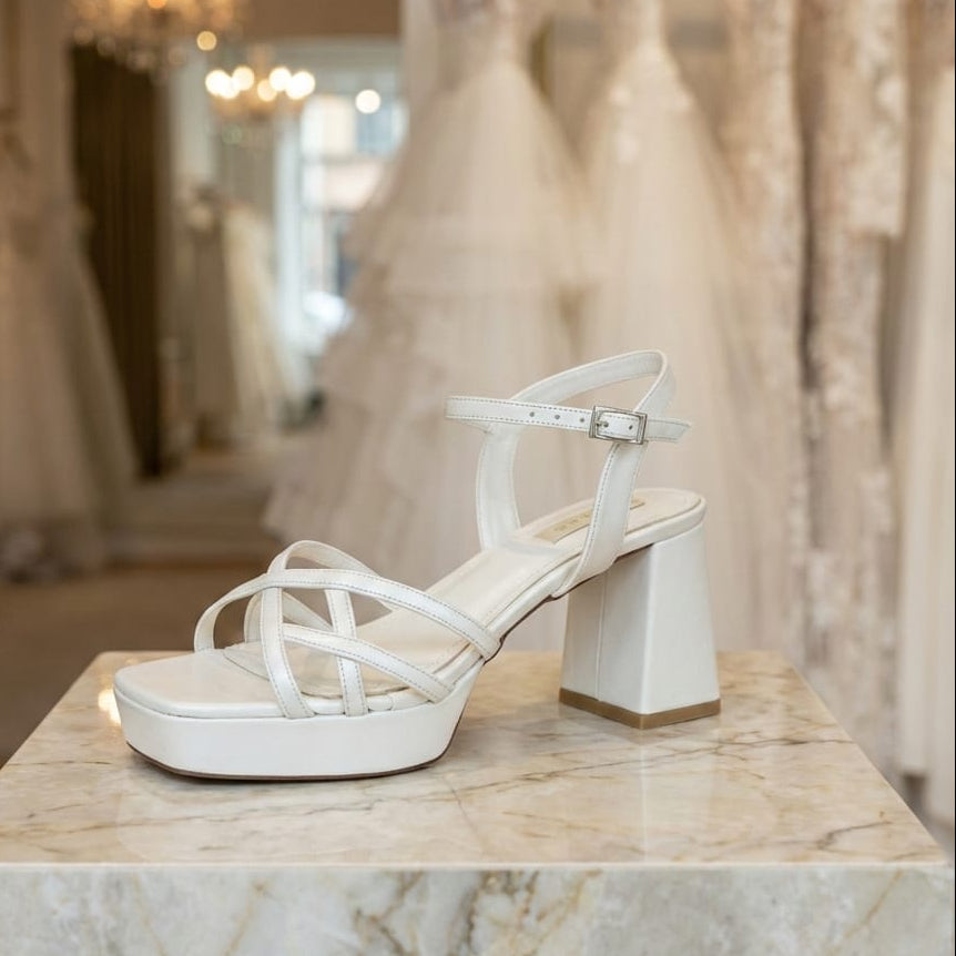 White Bridal sandal with a block heel on a marble surface with wedding dresses in the background in beirut Lebanon