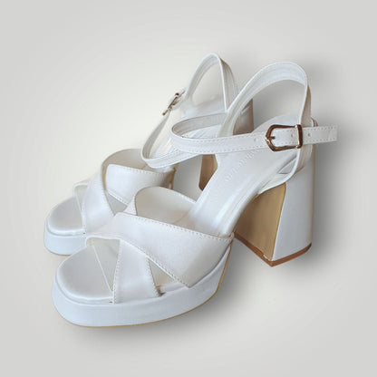 White block heel sandals with leather crisscross straps, ankle buckle closure, and platform sole