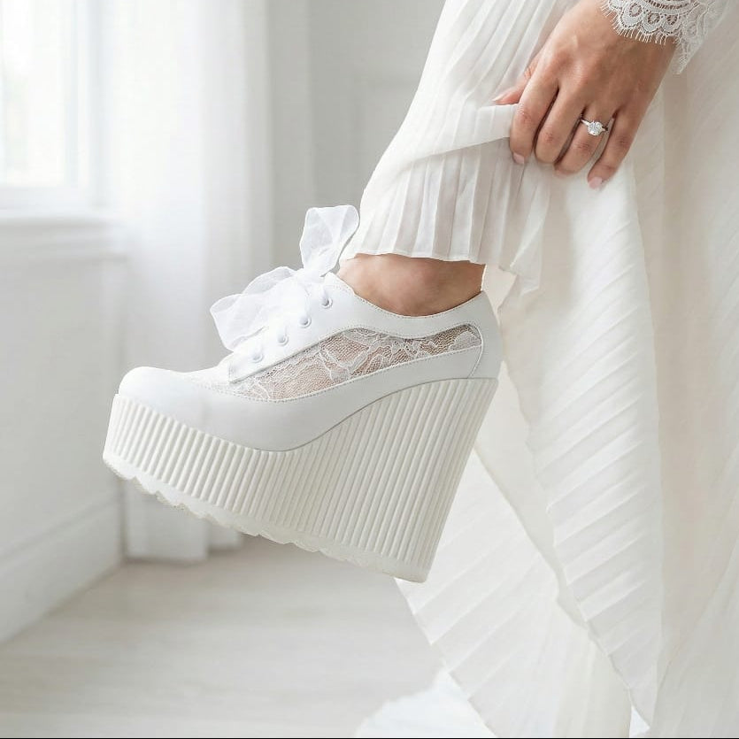 White platform wedge shoe with lace detailing worn by a person in a white dress. Beirut