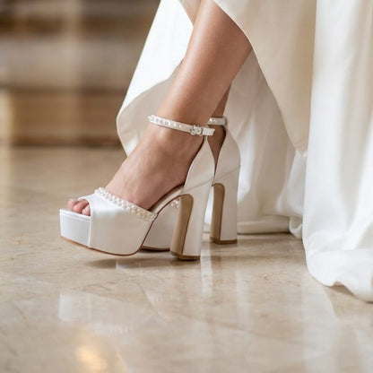  White wedding dress with bridal high-heeled shoes on a marble floor.
