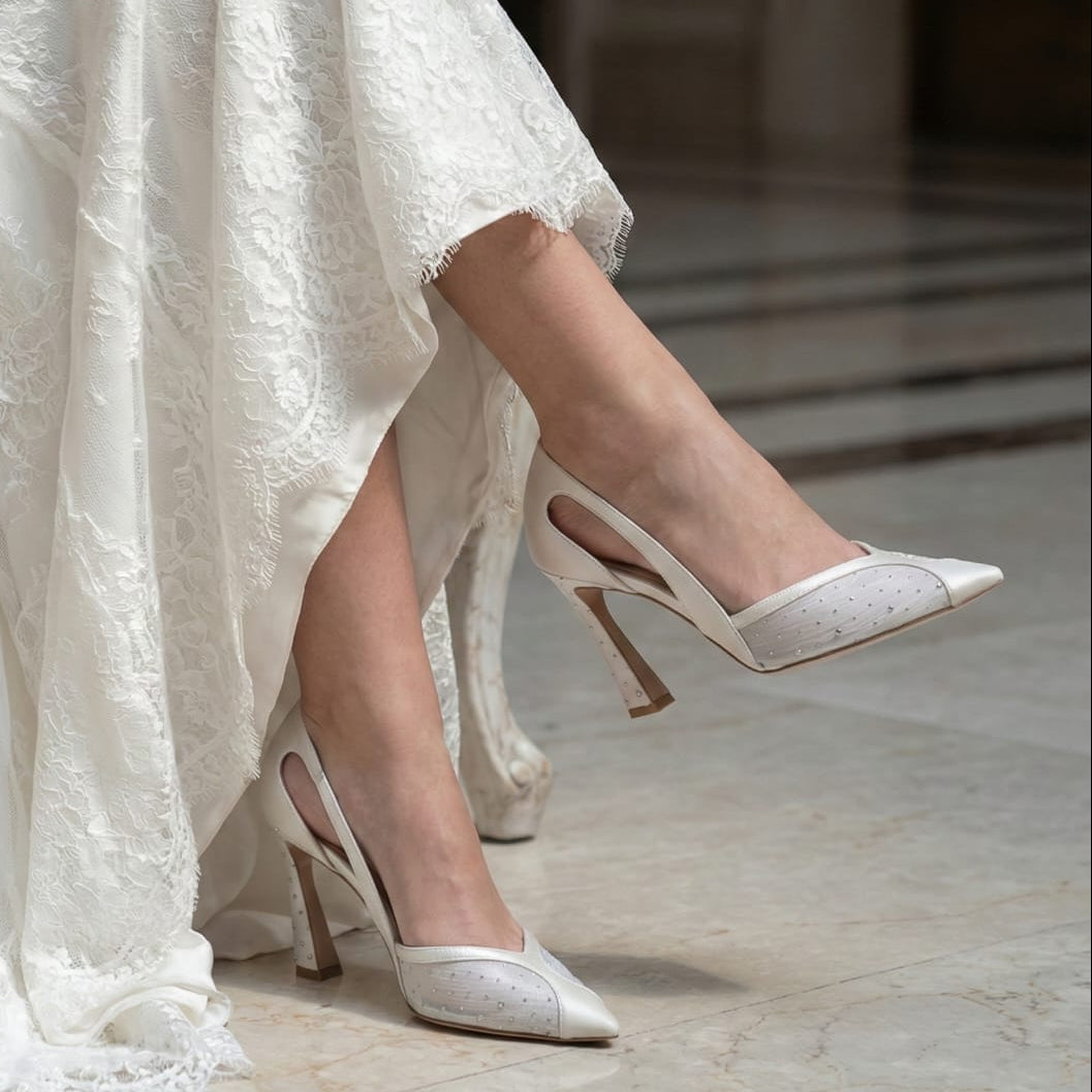 White wedding dress with bridal high-heeled shoes on a marble floor