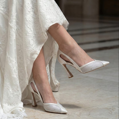 White wedding dress with bridal high-heeled shoes on a marble floor