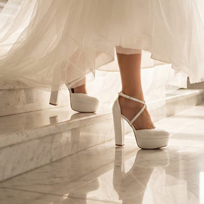 White wedding dress with bridal high-heeled shoes on a marble floor 