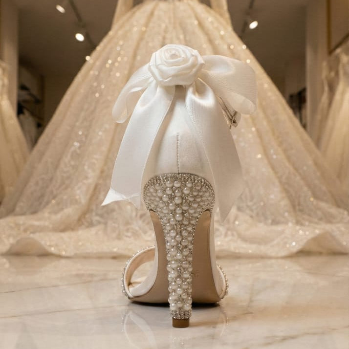 White wedding shoe with decorative bow and stiletto heel in a bridal store setting