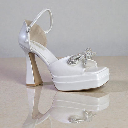 Smooth white bridal platforms with crystal bow detail. 