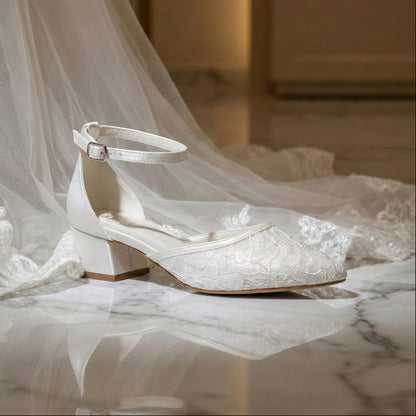 Comfortable low heel wedding shoes for brides with secure ankle buckle and soft lace upper on a marble floor.
