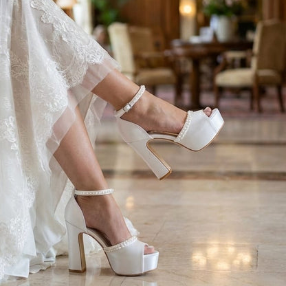 Person wearing white lace wedding shoes in a elegant indoor setting