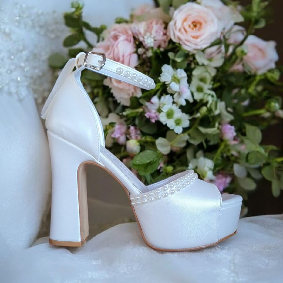  Elegant pearl-adorned block heel bridal shoes from White Lily Brides in Beirut, Lebanon. Features 12-13 cm heel and a 4.5 cm platform for comfort.
Image 2: Side view of White Lily Brides wedding heels, showcasing luxurious pearl details and a stable block heel design.