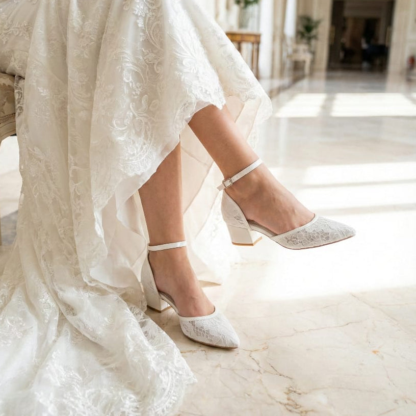 Elegant floral lace wedding pumps with satin heel cup and reflective marble background.