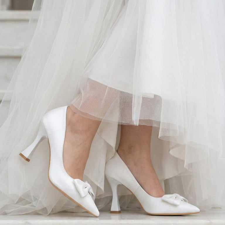 Modern white wedding shoes with a sculptural flared heel and bow accent, trending for brides in Beirut, Lebanon.