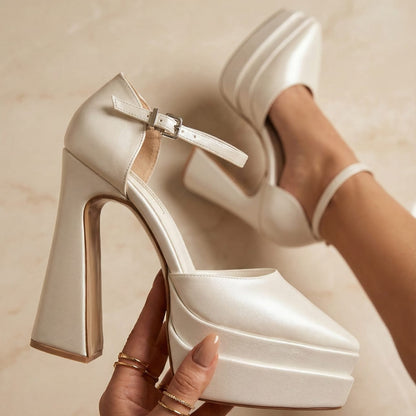 pearl White high-pointed heeled double semelle  shoes with a platform held by a hand against a neutral background