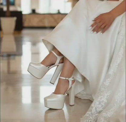 Bride wearing a white wedding dress and wedding high Heeled shoes on marble steps.