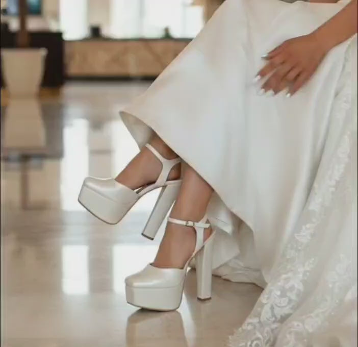 Bride wearing a white wedding dress and wedding high Heeled shoes on marble steps.