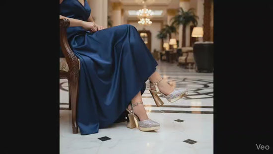 Gold high-heeled shoe with gemstone embellishments on a white background