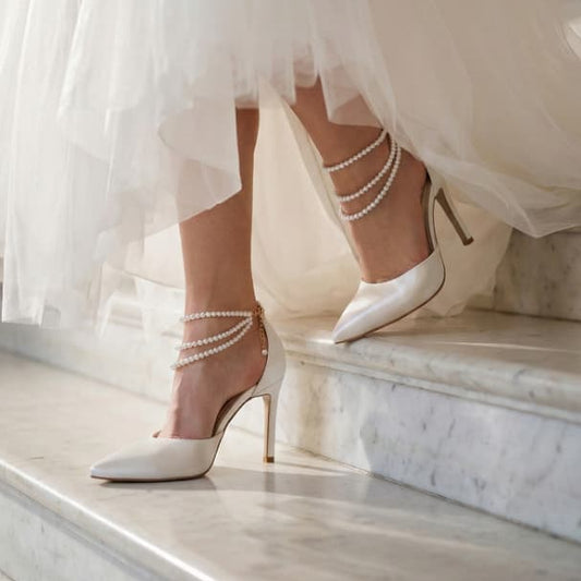 White wedding dress with high-heeled shoes on a marble staircase