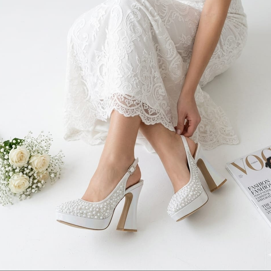 Bride in lace dress adjusting her pearl white double platform wedding shoes by White Lily Brides in Beirut, Lebanon.