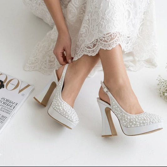Bride in lace dress adjusting her pearl white double platform wedding shoes by White Lily Brides in Beirut, Lebanon.