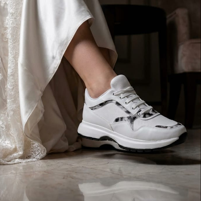 White Lily Brides luxury white sneakers with a detailed patterned trim and white laces, worn by a bride in a luxury hotel lobby with marble floors in Beirut, Lebanon.
