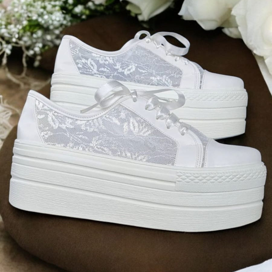 A pair of white lace bridal platform sneakers with a 7cm elevation, displayed on a stand.